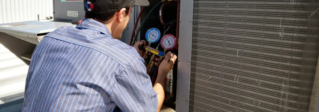 HVAC technician servicing a condenser unit in Minden